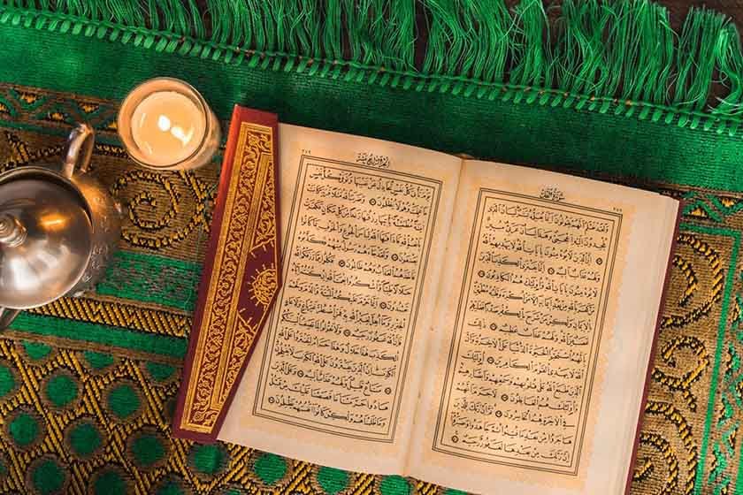 Pot and candle near opened book with Arabic language