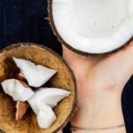 Hands holding two halves of a coconut after applying the best way to open a coconut