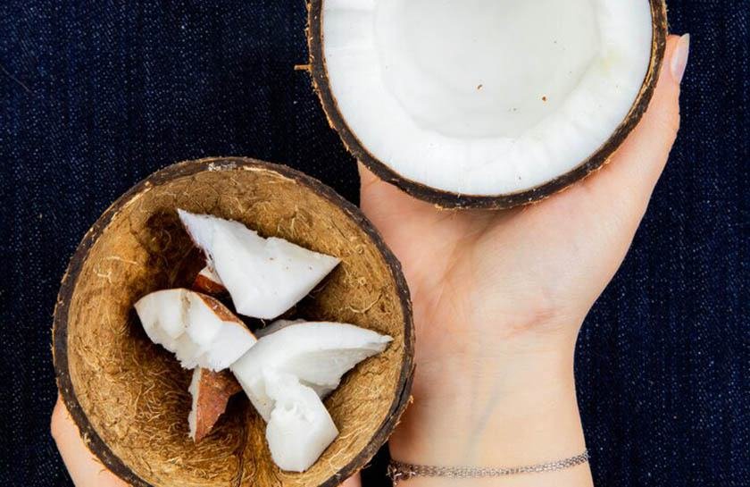 Hands holding two halves of a coconut after applying the best way to open a coconut