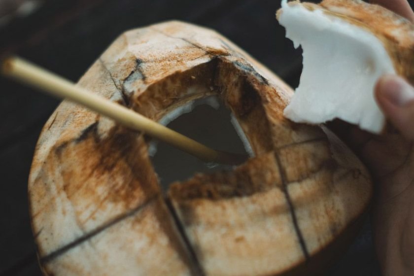 A coconut with the shell removed and a hole made to drink from with a straw