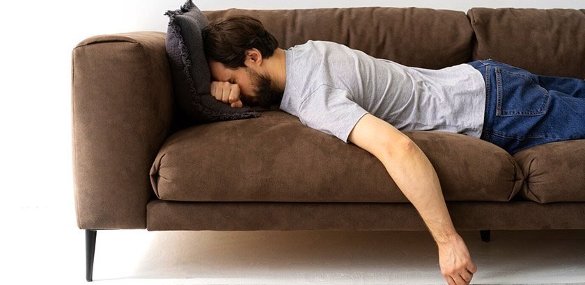 A man lying on his stomach on the couch after drinking too much