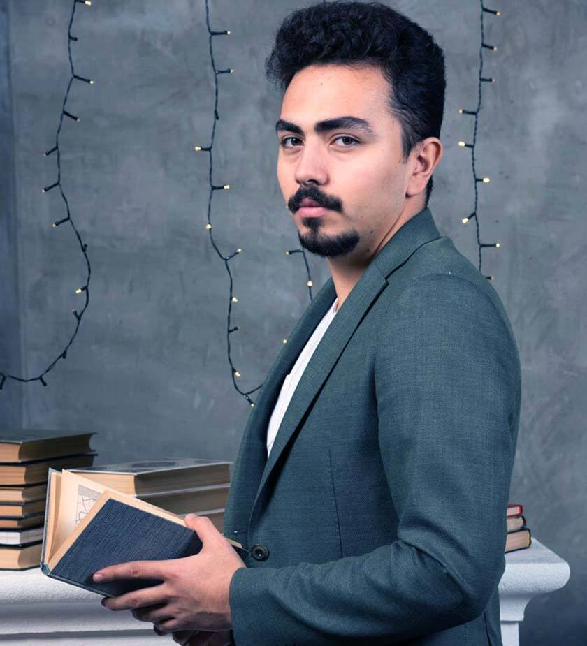 A man in a suit holding a book in a room with lights