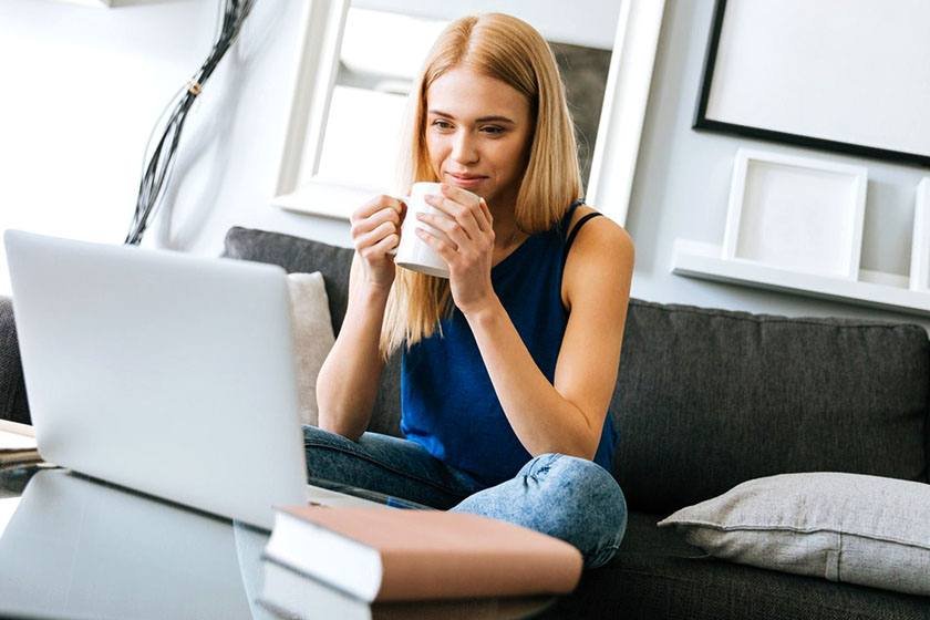 Woman holding a cup and watching online Spanish courses