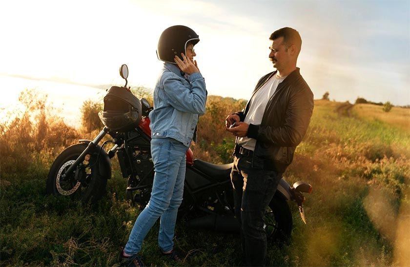 Man and woman next to a motorbike at sunset