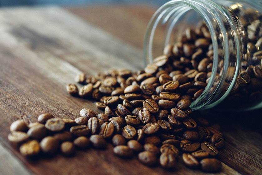 Close-up photo of scattered coffee beans from a jar which can be the best way to store coffee beans