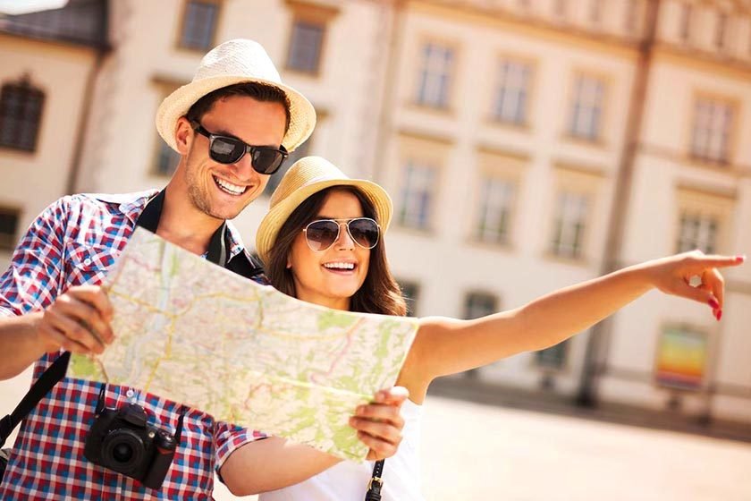 Smiling man and woman with glasses looking for route on paper map