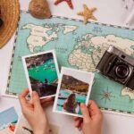 Pictures held by hands that are on a table on which there is a camera, binoculars, a world map and a hat, which can be part of the best way to travel europe