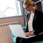 A woman seating on a couch and searching in her laptop for the best way to advertise HVAC business online