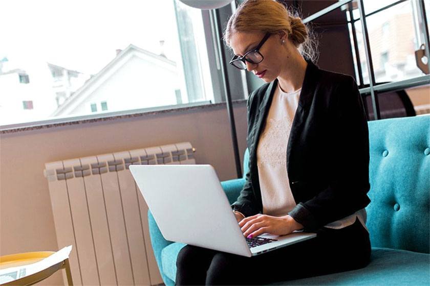 A woman seating on a couch and searching in her laptop for the best way to advertise HVAC business online