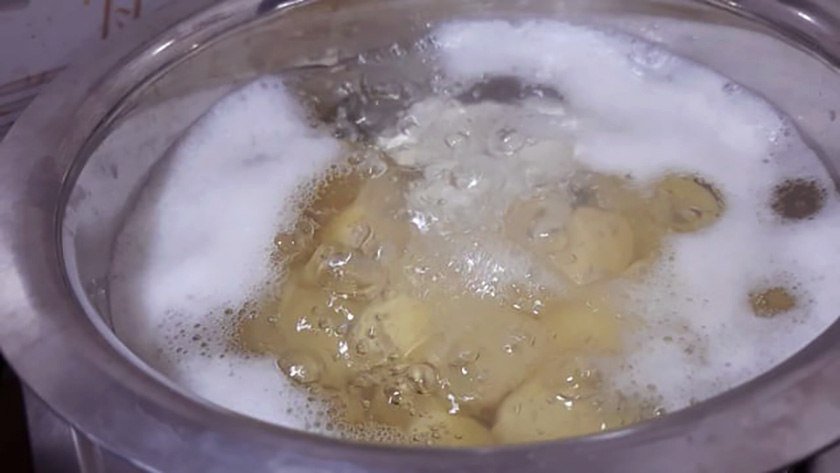 A pot of boiling water with chicken in it