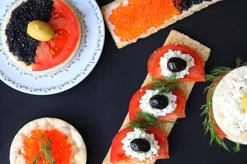 Table pictured above with caviar, tomato slices, cream cheese and olives