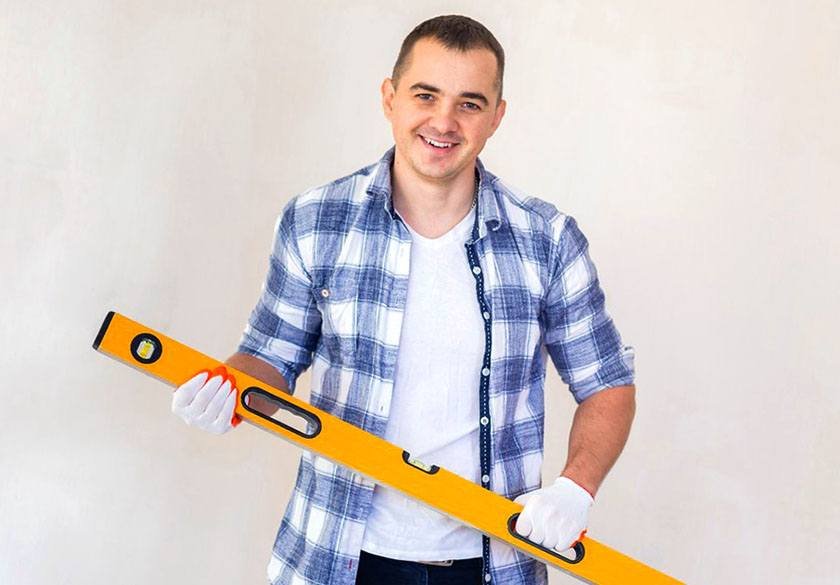 A man holding a large orange colored level