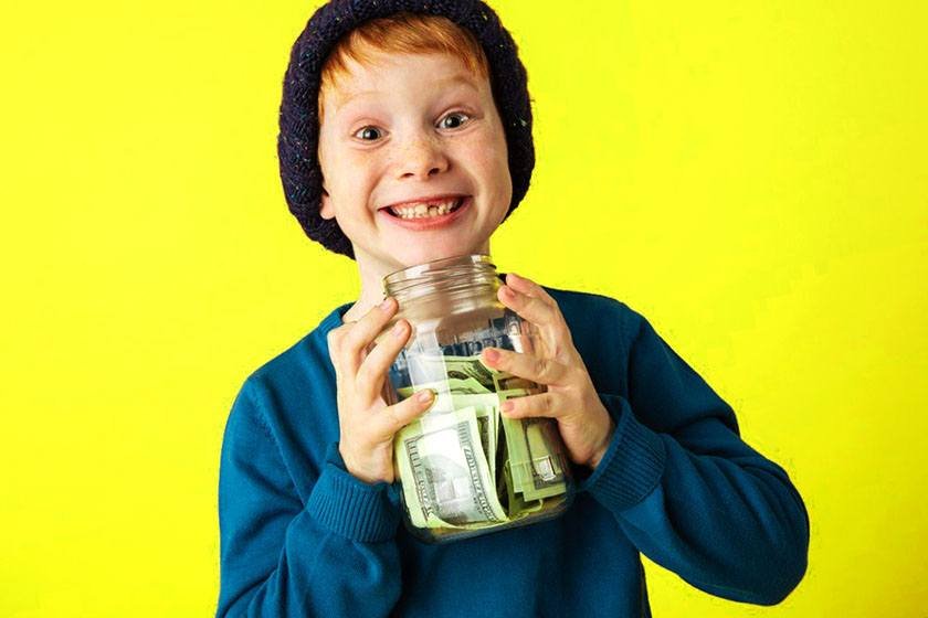 Smiling boy holding a jar of money