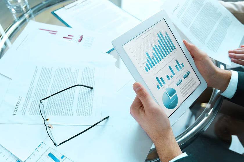 A man with a tablet on a table full of documents