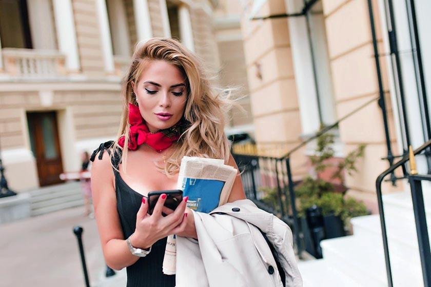 A blonde lady on the streets of Paris uses her phone to learn French