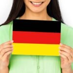 A woman in green dress held German flag which is one of the best way to learn German