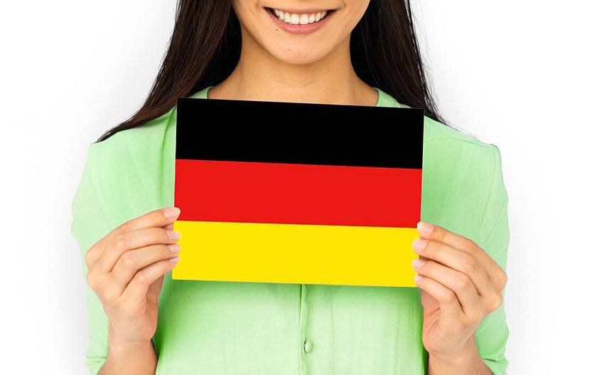 A woman in green dress held German flag which is one of the best way to learn German