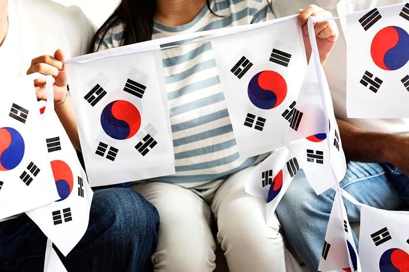 Several people hold flags with the flag of South Korea