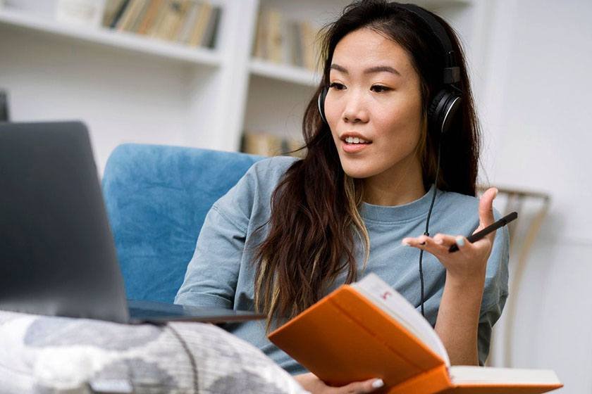 Woman with headphones, notebook and laptop learning Mandarin online