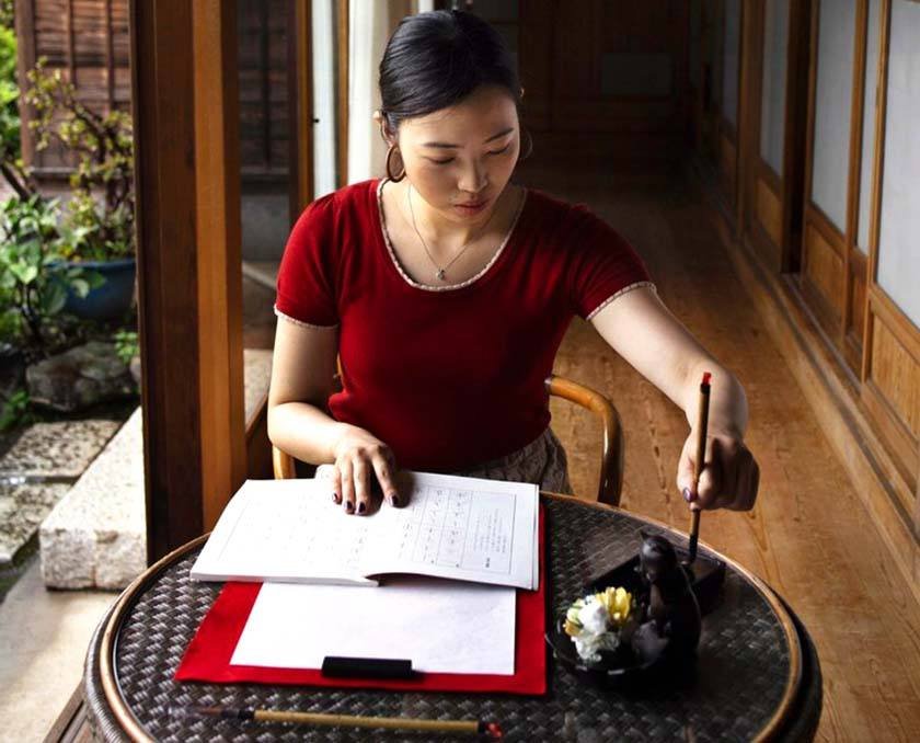 A woman sitting in front of a table practices the Mandarin language