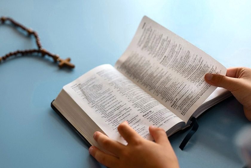 Picture of hands holding the bible and a Chain with a cross, which is the best way to read the bible