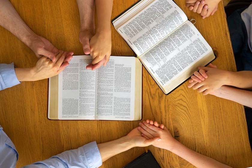 High angle shot of a family holding hands while holding open Bibles