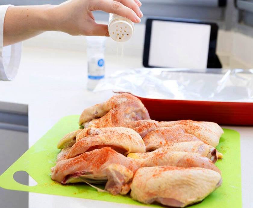 A hand sprinkles salt on chicken nuggets