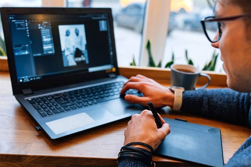 A man is processing a photo on his laptop