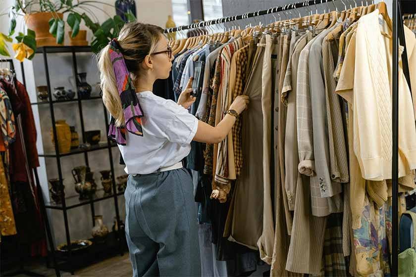 Woman in back selecting second hand clothes from hanger