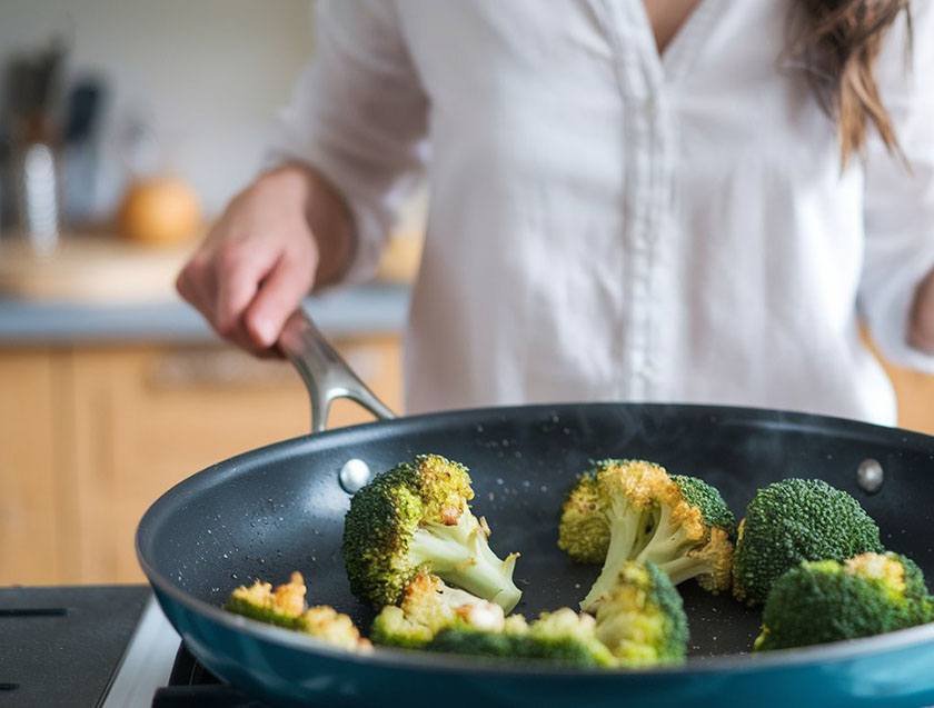 A woman in her kitchen is using the best way to steam broccoli