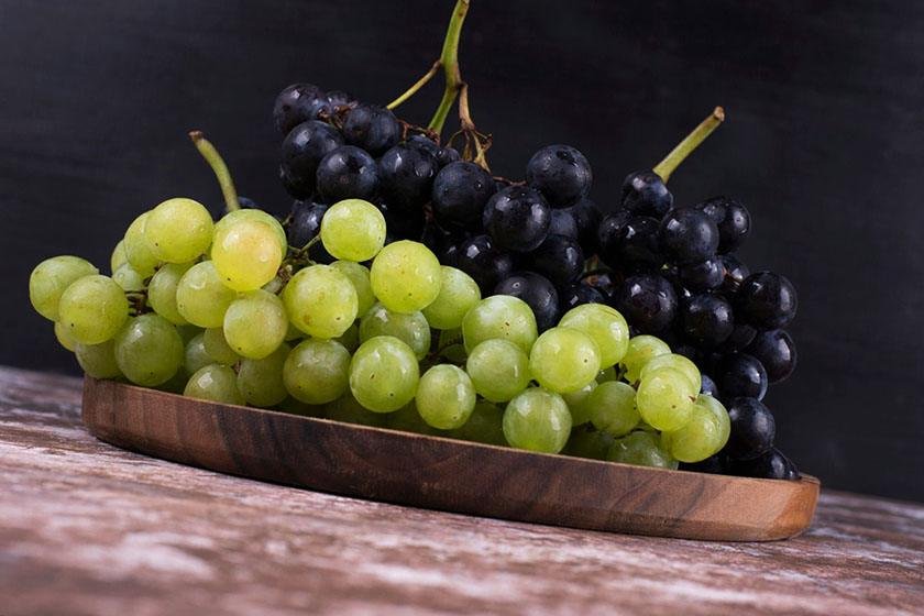 Two varieties of grapes on a wooden plate that can be the best way to store grapes