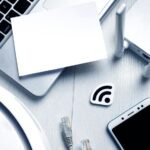 A laptop, a piece of paper, a phone, a router and cables are part of the process for the best way to extend wifi range