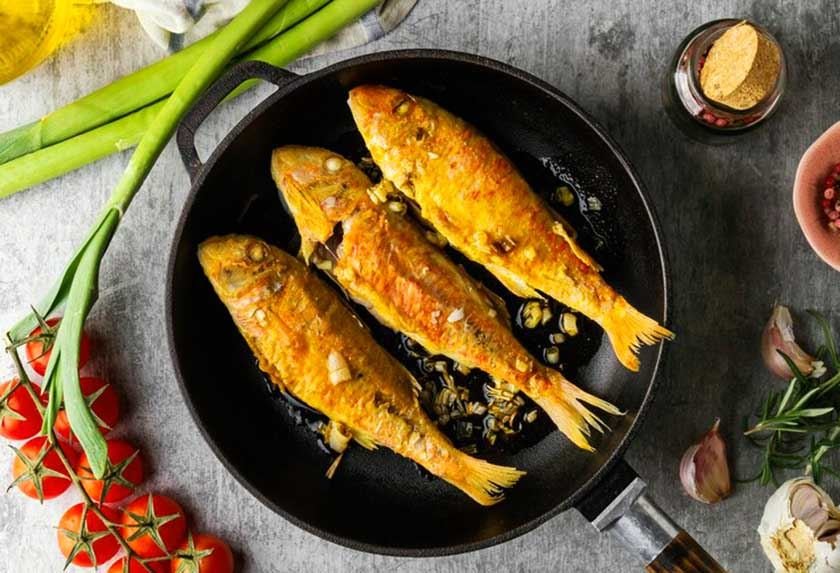 Crispy fish in a pan with tomatoes, leeks and spices around it is the best way to fry fish