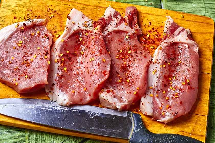 The best way to season pork chops on a wooden cutting board with a knife