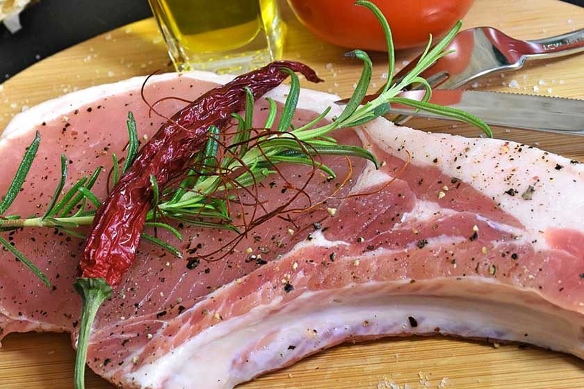 Raw pork chop topped with hot pepper and seasoning