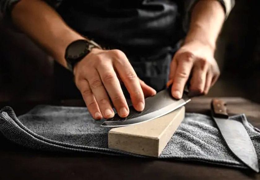 A man sharpens a kitchen knife on a special whetstone