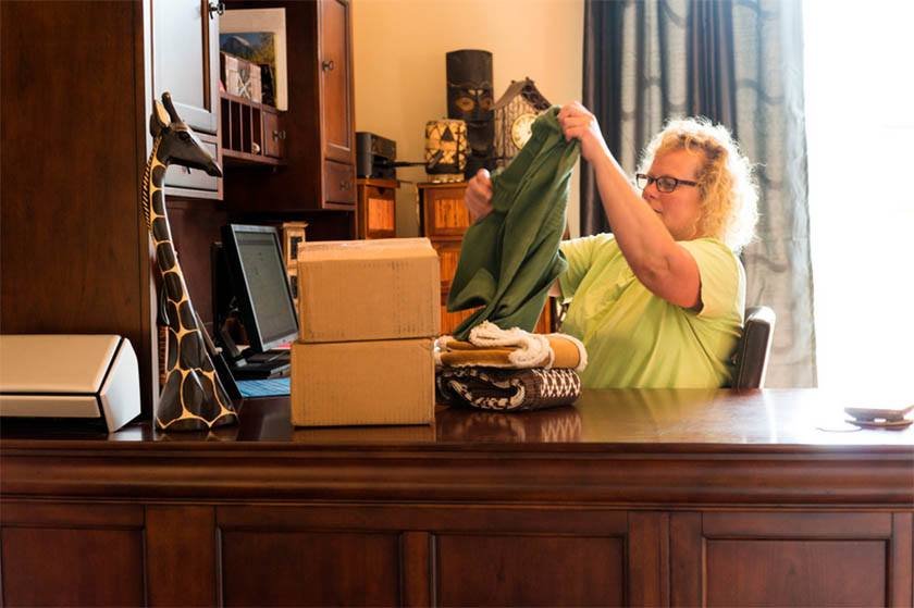 A woman holding a dress while sitting in her office 