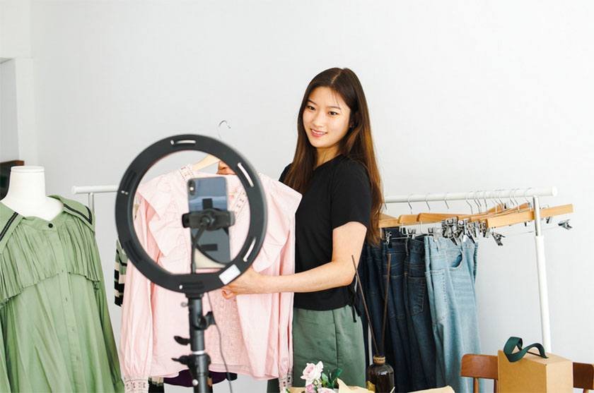 A young woman takes pictures of her pink dress for online selling