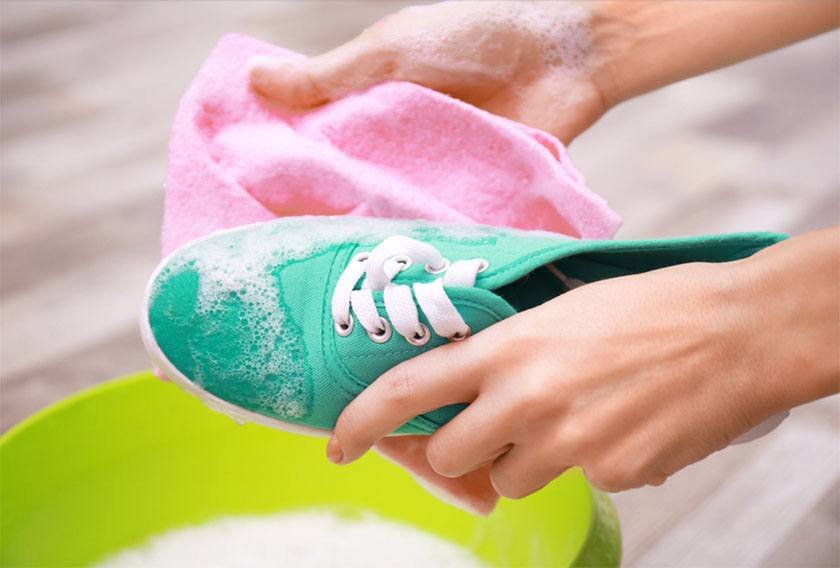 A woman washes green sneakers