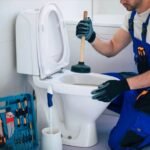 A worker performs the best way to unclog the toilet with a plunger